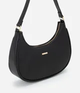 Cartera tipo baguette color negro, confeccionada en PU con acabado liso. Cuenta con cierre de cremallera y herrajes en tono dorado claro. El asa es ajustable y tiene un pequeño logo metálico de la marca Satinato en el frente.