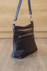 Cartera de cuero color beige, de diseño estructurado, con bolsillo frontal con cierre y detalles en cuero grabado con efecto reptil. Cuenta con correa ajustable para llevar al hombro o cruzada.