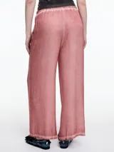 Pantalon de corte amplio y relajado, confeccionado en viscosa con acabado satinado y efecto lavado. Presenta cintura elastizada y detalles de desgaste en costuras y ruedo.