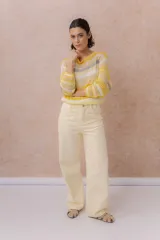 Pantalón de jean de tiro medio-alto y pierna amplia con caída recta, color amarillo manteca, con diseño clásico de cinco bolsillos y cierre delantero con botón.