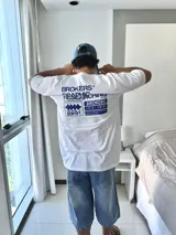 Remera blanca de manga corta con estampado gráfico en azul en la espalda, que incluye el texto "BROKERS GRAPHIC RESEARCHING" y varios logos de la marca.