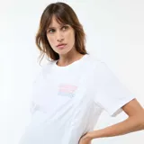 Camiseta de lactancia blanca de manga corta, con cuello redondo y estampa frontal con texto y diseño de tablero de ajedrez. Presenta aberturas laterales discretas para facilitar la lactancia.