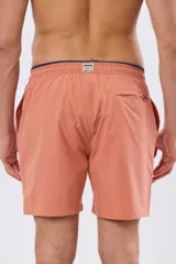 Short de baño liso color coral, confeccionado en tela flexible elastizada, con diseño versátil para uso dentro y fuera del agua.