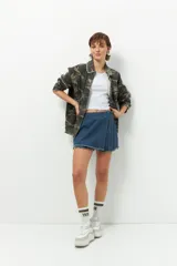 Short pollera de jean prelavado color negro, con lazo en uno de sus laterales y detalle de flecos en las terminaciones.