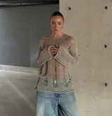 Buzo de punto calado con diseño desgastado y roturas verticales en color cemento. Presenta escote bote, mangas largas y una silueta holgada con terminaciones desflecadas.