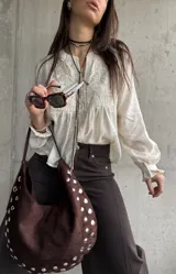 Camisa beige de manga larga, con detalles bordados en el frente y botones decorativos.