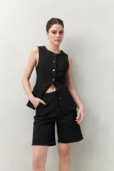 Bermuda negra de tiro medio con silueta recta y largo a la altura de la rodilla. Presenta bolsillos laterales y traseros, y costuras visibles.