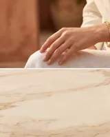 Pulsera tipo esclava rígida de acero con baño de oro, con diseño de eslabones texturizados y esferas lisas intercaladas.