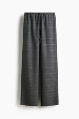 Pantalón holgado de pierna recta y tiro medio, confeccionado en tejido a cuadros gris. Presenta cintura elástica con cordón ajustable y bolsillos laterales.