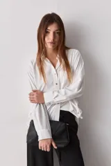 Camisa celeste de calce relajado, con cuello camisero, bolsillo aplicado en el pecho y mangas largas con puños abotonados. Cuenta con lazos ajustables en los laterales para fruncir y regular la silueta.