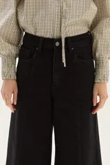 Jean de tiro alto, pierna ancha y color negro. Presenta costuras marcadas en el frente que recorren verticalmente la pierna.