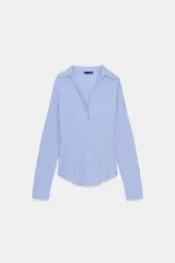 Camisa de manga larga con cuello solapa y escote en pico. Presenta un diseño entallado en la cintura y cierre frontal mediante botones.