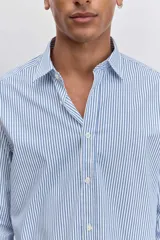 Camisa de corte regular, color celeste con rayas verticales blancas muy finas, cuello clásico y mangas largas con puños abotonados.