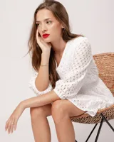 Vestido corto negro de broderie de algodón, con escote en V, mangas tres cuartos, cintura elastizada, falda corte A con volado y forro interior.