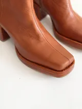 Bota de caña media color óxido, confeccionada en cuero, con plataforma y taco cuadrado texturizado, punta cuadrada y cierre lateral.
