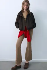 Pantalón de corte flare confeccionado en mezcla de algodón con efecto lavado. Presenta tiro medio, cintura elástica y detalles de tachas y aplicaciones bordadas en el bajo de las piernas.