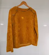 Sweater de chenille color mostaza, de cuello redondo, con mangas largas y apliques de pana acanalada en los hombros decorados con botones.