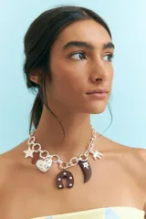 Collar plateado de cadena gruesa con dijes colgantes de estrella, corazón, herradura y cuerno.