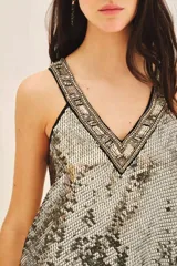 Vestido corto de corte recto y sin mangas, confeccionado en viscosa con bordado integral de lentejuelas en tonos dorados y plateados. Presenta un escote en V con una guarda bordada a mano que incluye piedras, mostacillas y lentejuelas.