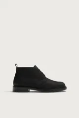 Bota de caña baja con cordones, confeccionada en piel con acabado abatanado de color negro, horma redonda y suela con ligero tacón.