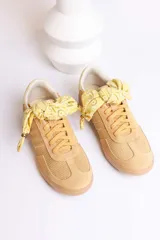 Zapatillas bajas color marrón con cordones y charms dorados.