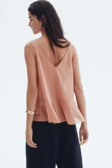 Musculosa color salmón con escote en V pronunciado, breteles anchos y detalle de volados en el escote y en el bajo de doble capa.