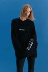 Sweater oversize de tejido de punto grueso en color negro, con cuello redondo y diseño de estampado gráfico en el pecho y en una de las mangas. Presenta un acabado desgastado que le otorga un estilo vintage.