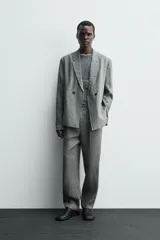 Pantalón de corte straight relaxed fit confeccionado en tejido de lino. Presenta cintura con pliegues frontales, cierre frontal con cremallera y botón, bolsillos laterales y bolsillos traseros con solapa.