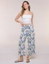 Pantalón crop de lino y rayón, con diseño wide leg de corte holgado, estampado tropical de hojas en tonos verde, azul y marrón sobre fondo blanco. Cuenta con pretina trasera elastizada y bolsillos delanteros.