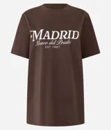 Remera marrón de algodón con cuello redondo y mangas cortas. Estampado frontal con la leyenda "Madrid Museo del Prado EST 1987" en color blanco.