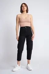 Jean de corte mom fit en color negro, con diseño de cinco bolsillos, cierre de cremallera y botón frontal.