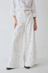 Pantalon de corte wide leg y tiro alto, color blanco con estampado de figuras deportivas pequeñas. Presenta cierre frontal con botón y bolsillos laterales.