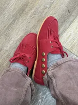 Náuticos de gamuza color rojo con flecos en la parte delantera, cordones al tono y detalle de tachas metálicas en los laterales.