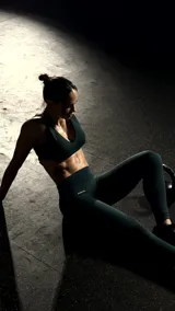 Legging deportivo de tiro alto en color verde oscuro, confeccionado con tecnología sin costuras (seamless), control de abdomen y diseño de paneles texturizados.