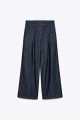 Pantalón culotte de denim azul oscuro, tiro medio, con cintura elástica en la parte trasera, bolsillos laterales y pinzas delanteras. Cierre frontal con cremallera, botón y ganchos metálicos.