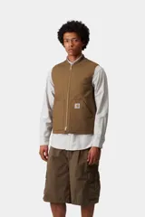 Chaleco de trabajo Carhartt WIP, color azul marino, con cierre frontal completo, cuello tipo bomber y bolsillos delanteros. Presenta el logo de la marca bordado en el pecho.
