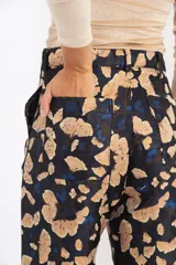 Pantalón de brocato con estampado de hojas de ginkgo en tonos azulados y beige, tiro medio y piernas rectas.