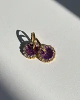 Aros de acero quirúrgico con dije circular de resina rosa y borde de strass dorados.