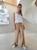 Pantalón de corte holgado y tiro medio, confeccionado en tejido brillante color dorado con acabado metalizado. Presenta cintura elástica con cordón ajustable y bolsillos laterales.