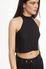 Top de punto estilo halter, color crudo, con cuello alto ajustado, diseño sin mangas y corte corto.