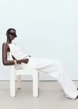 Pantalón de jean estilo wide leg, color blanco, con tiro bajo, cierre de botón y cremallera, y diseño de cinco bolsillos.