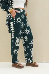 Pantalón verde oscuro con estampado abstracto en color blanco, de corte holgado y cintura elástica con cordón ajustable.