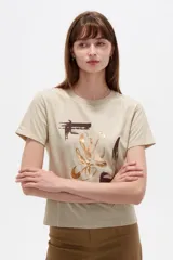 Remera de manga corta de algodón en color blanco, con cuello redondo y diseño holgado. Presenta un estampado frontal con detalle de acabado metálico (foil).