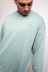 Buzo verde agua liso, de corte oversize, confeccionado con 60% algodón y 40% poliéster.