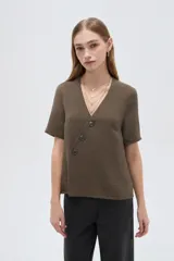 Blusa marrón de manga corta con cuello en V y cierre frontal cruzado con tres botones.