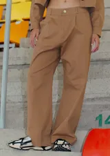 Pantalón de estilo sastrero confeccionado en gabardina elastizada color camel, con corte recto, bolsillos delanteros y tajo en el lateral interno del ruedo.