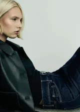 Falda corta de jean en color azul oscuro, con diseño entallado, cinco bolsillos, trabillas para cinturón y una abertura frontal en el bajo.