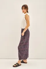 Pantalón tipo babucha o pirata de viscosa, color azul marino con estampado en tonos rojizos y blancos. Presenta un corte amplio, bolsillos laterales y cintura elástica.