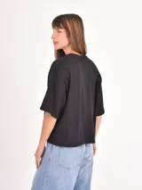 Remera de corte boxy y holgado, con cuello redondo y mangas cortas, en color negro liso.