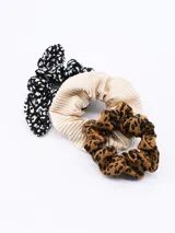 Set de tres scrunchies para el pelo, uno con estampado de manchas en blanco y negro, otro color beige plisado y otro con estampado animal print.